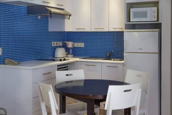 Kueche im Callisto Holiday Village mit blauen Fliesen und weissen Mobelstucken.