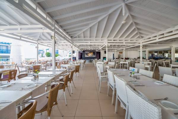 Innenansicht des Restaurants im Callisto Holiday Village mit leeren Tischen und Stühlen.
