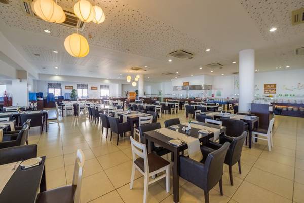 Innenansicht des Restaurants im Callisto Holiday Village mit vielen gedeckten Tischen und Stühlen.