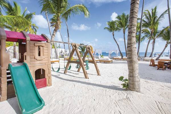 Spielplatz am Strand des Sunscape Coco Punta Cana Hotels mit Palmen und Ozean im Hintergrund.
