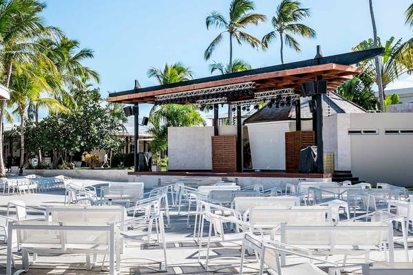 Gartenbereich des Sunscape Coco Punta Cana Hotels mit weißen Stühlen und einer Bühne.