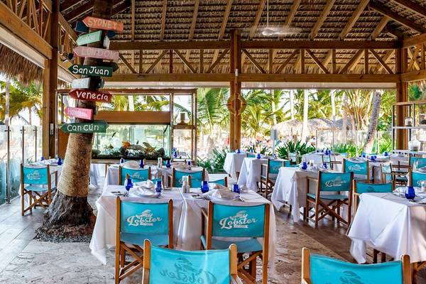Innenbereich des Restaurants im Sunscape Coco Punta Cana Hotel mit blauen Stühlen und weißen Tischdecken.