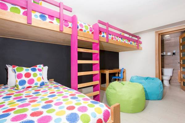 Ein Kinderzimmer mit bunten Etagenbetten, bunten Kissen und zwei farbigen Sitzsäcken.