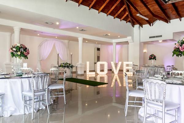 Hochzeitssaal im Sunscape Coco Punta Cana mit großen LOVE-Buchstaben und gedeckten Tischen.