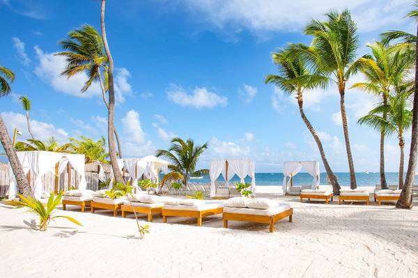 Sonnensegel am Strand von Sunscape Coco Punta Cana mit weißen Sonnenbetten und Palmen