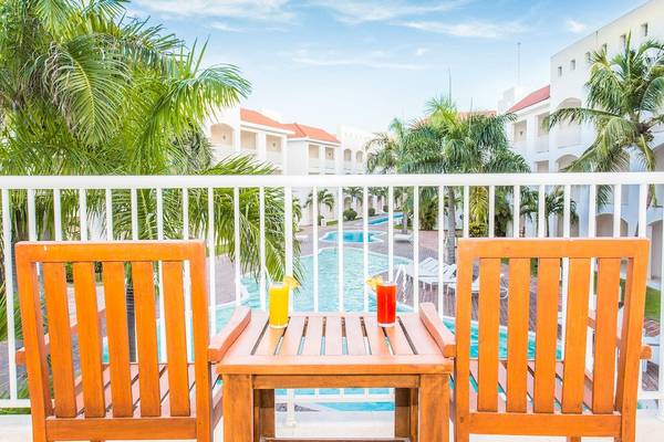 Zwei Holzstühle mit Getränken auf dem Balkon im Sunscape Coco Punta Cana Hotel.
