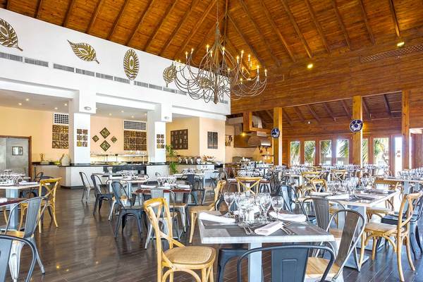 Innenraum eines Hotels mit Holzdecken und einem großen Kronleuchter, gefüllt mit Tischen und Stühlen.