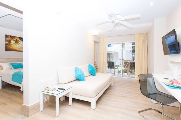 Innenansicht eines Zimmers im Sunscape Coco Punta Cana mit Bett, Sofa und Schreibtisch.