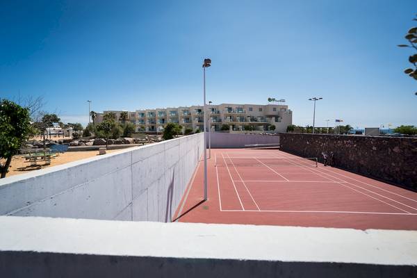 Tennisplatz im HD Beach Resort mit Blick auf das Hotelgebäude.