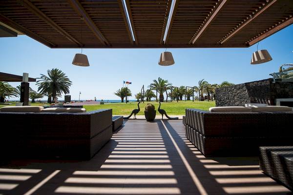 Außenbereich des HD Beach Resorts mit Loungesofas, Palmen und Meerblick.