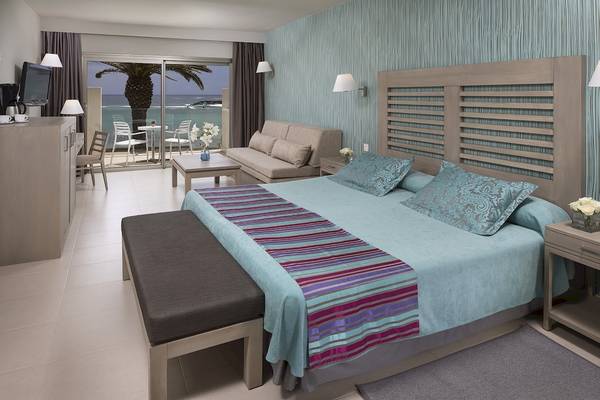 Schlafzimmer im HD Beach Resort mit Meerblick, Doppelbett, Sofa, Tisch und Terrassenmöbeln.
