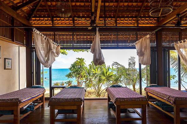 Massageraum im Saree Samui Resort mit Blick auf das Meer und Palmen.
