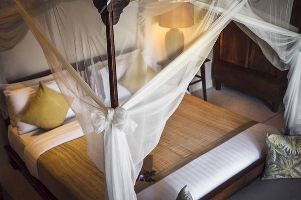 Ein Bett mit Baldachin im Saree Samui Resort, mit weißen Laken und gelben Kissen.