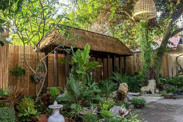 Tropischer Garten im Saree Samui Resort mit einer kleinen strohgedeckten Hütte.