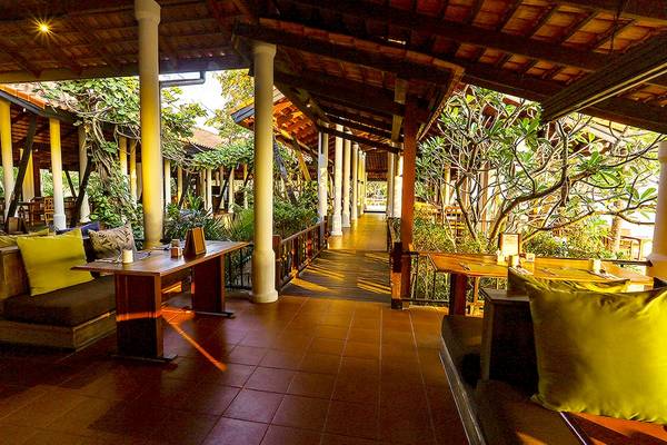 Außenbereich des Saree Samui Resorts mit gelben Kissen und Holztischen.