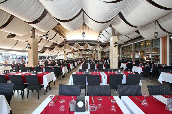 Innenraum des Restaurants im Club Yali Hotels & Resort mit vielen gedeckten Tischen und Stühlen.