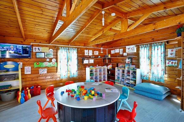 Kinderzimmer im Club Yali Hotels & Resort mit Holzwänden, Spielzeug und bunten Stühlen.