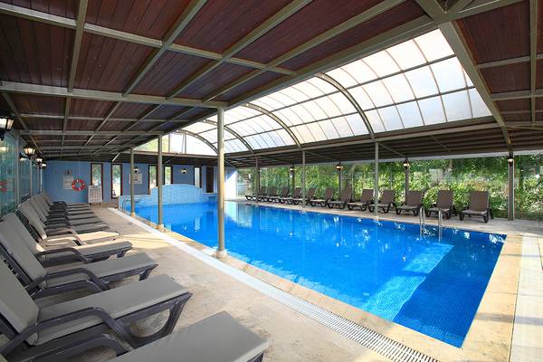 Das Club Yali Hotels & Resort bietet einen Swimmingpool mit Sonnenliegen und einer Glasdachkonstruktion.