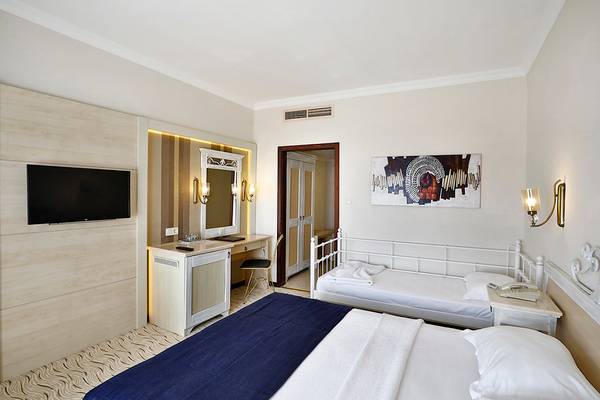 Hotelzimmer im Club Yali Hotels & Resort mit Bett, Fernseher und Schreibtisch.