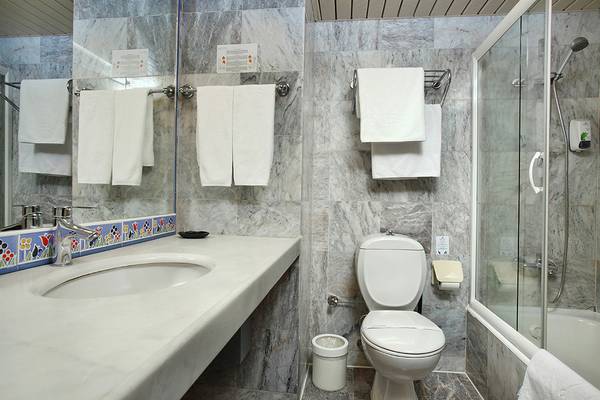 Badezimmer im Club Yali Hotels & Resort mit Marmorfliesen und Glasdusche.