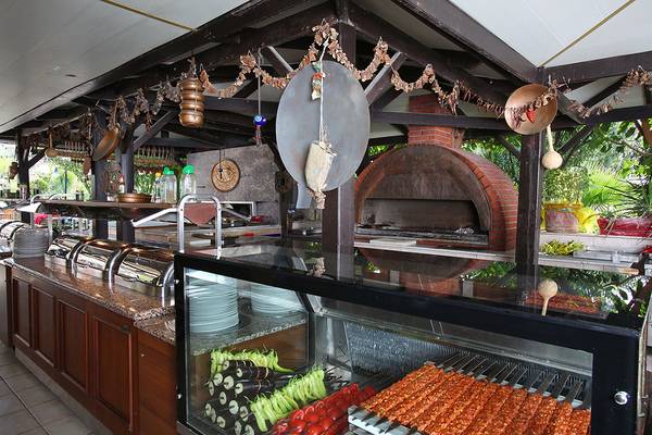 Innenbereich des Restaurants im Club Yali Hotels & Resort mit Grill, vorbereiteten Speisen und rustikalem Ambiente.
