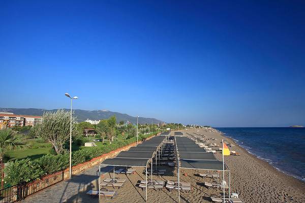 Strand des Club Yali Hotels & Resorts mit Sonnenliegen und Sonnenschirmen