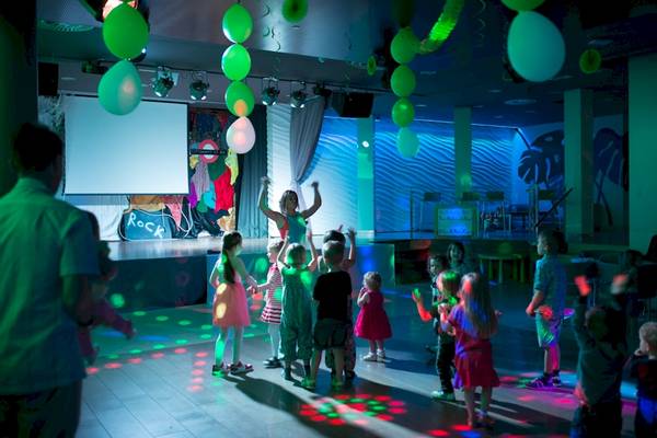 Kinder tanzen auf einer Party im HD Beach Resort mit bunten Lichtern und Heliumballons.