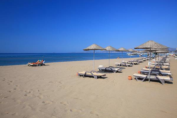 Strand des Club Yali Hotels & Resort mit vielen Sonnenliegen und Sonnenschirmen