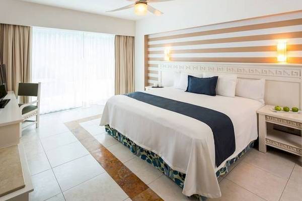 Schlafzimmer im BlueBay Grand Esmeralda Hotel mit Bett, Schreibtisch, Stuhl und Fenstern.