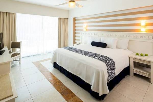 Schlafzimmer im BlueBay Grand Esmeralda Hotel mit Bett, Schreibtisch, Stuhl und Fenstern.