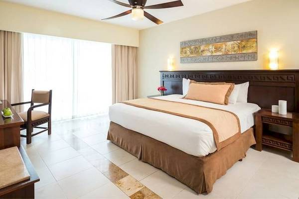 Schlafzimmer im BlueBay Grand Esmeralda Hotel mit Bett, Deckenventilator, Tisch und Stuhl.