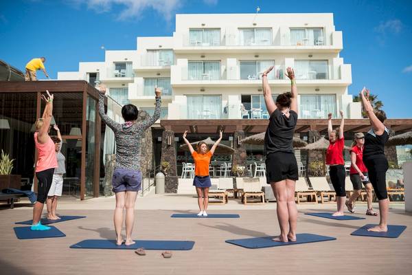 Gruppe von Menschen, die Yoga vor dem HD Beach Resort Hotel machen