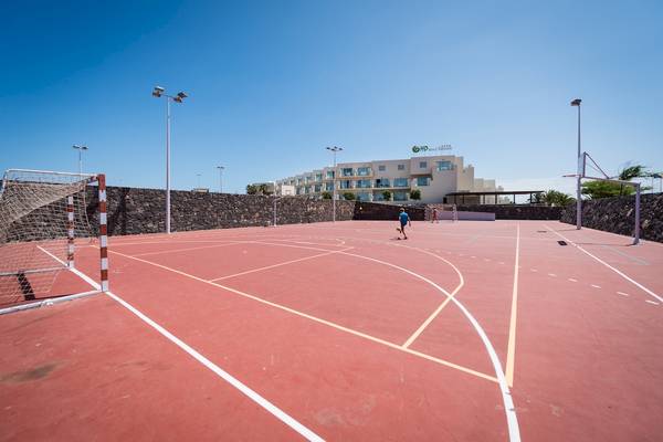 Sportplatz vor dem HD Beach Resort Hotel mit zwei Spielern und einer Mauer.