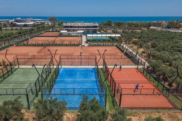 Luftaufnahme des Tennisplatzes der Lyttos Beach Tennis Academy mit Blick auf mehrere Tennisplätze, Gebäude und Meer.