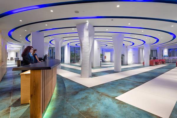 Lobby des Lyttos Beach Hotels mit Rezeptionstresen, blauer Beleuchtung und modernen Möbeln.