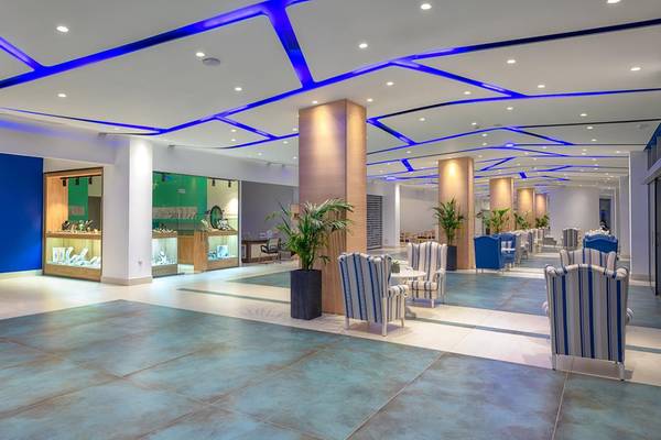 Lobby des Lyttos Beach Hotels mit blauen Lichtern an der Decke und Möbeln.