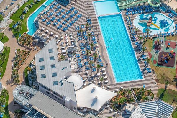 Luftaufnahme des Poolbereichs des Lyttos Beach Hotels mit Swimmingpools, Wasserrutschen und Sonnenliegen.