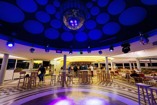 Innenbereich der Bar im Lyttos Beach Hotel mit geometrischem Bodendesign und blauer Beleuchtung.