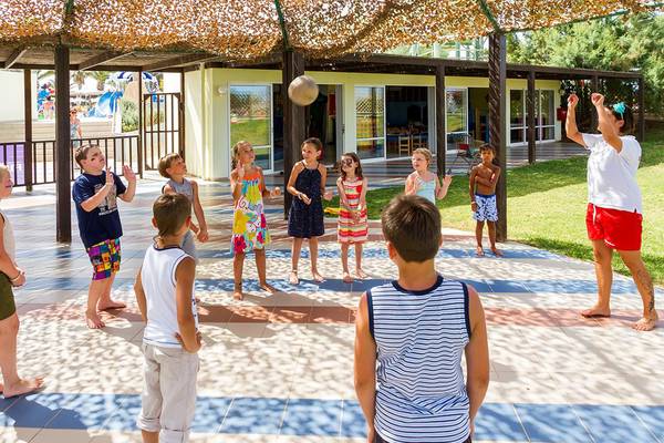 Kinder spielen Volleyball unter einem Schattendach im Lyttos Beach Hotel.