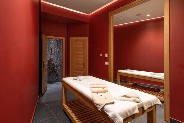 Innenansicht des Saunabereichs im Lyttos Beach Hotel mit roten Wänden und zwei Massagetischen.