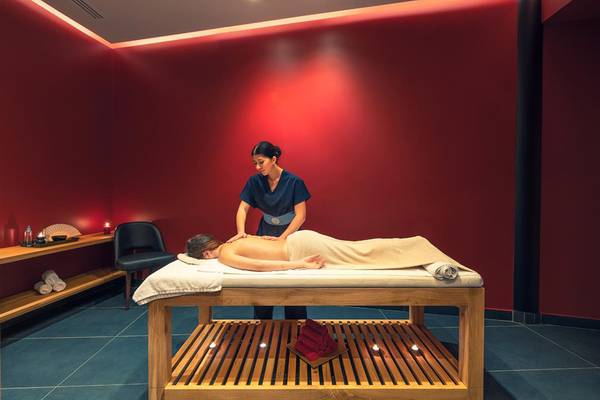 Eine Frau genießt eine Massage in einem roten Behandlungsraum im Lyttos Beach Hotel.