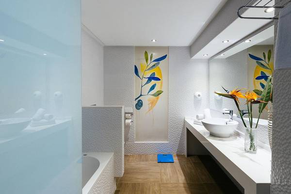 Innenansicht des Badezimmers im Lyttos Beach Hotel mit Badewanne, Waschbecken und Dekoration.