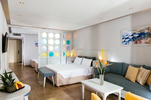 Innenansicht des Lyttos Beach Hotels mit Schlafzimmer, Bett, Sofa und Tisch.