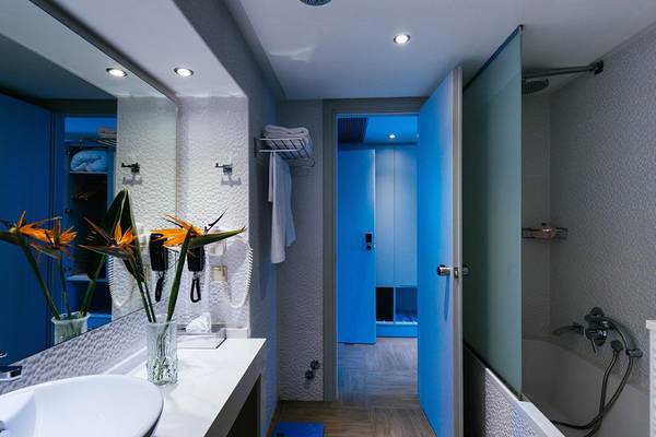 Badezimmer im Lyttos Beach Hotel mit blauen Wänden, einer Dusche und einem Waschbecken.