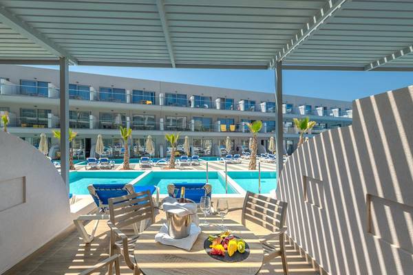 Terrasse mit Poolblick im Lyttos Beach Hotel mit blauen Sonnenliegen und Früchteplatte.