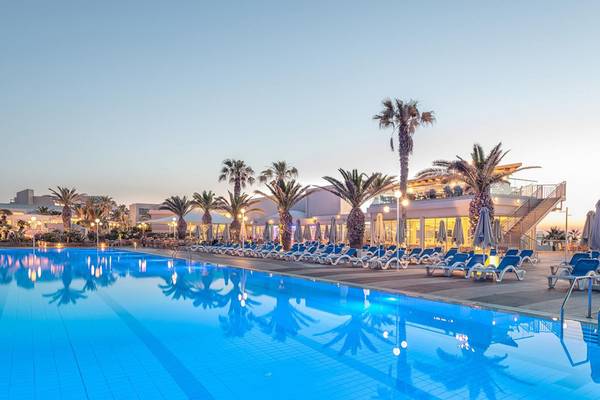 Außenpool am Abend im Lyttos Beach Hotel mit Loungestühlen und Palmen