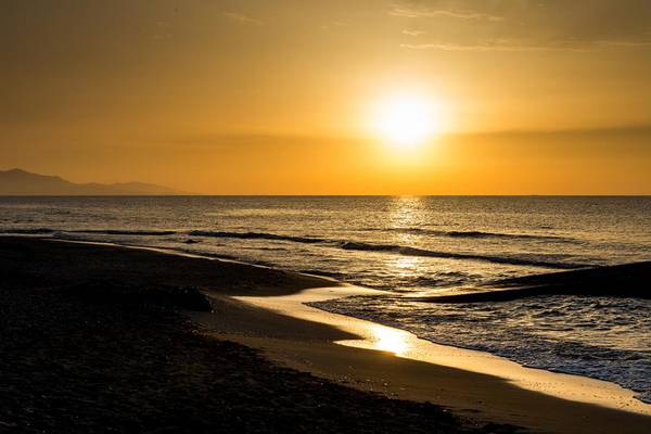 Sonnenuntergang am Lyttos Strand mit goldenen Lichtstrahlen auf dem Wasser.