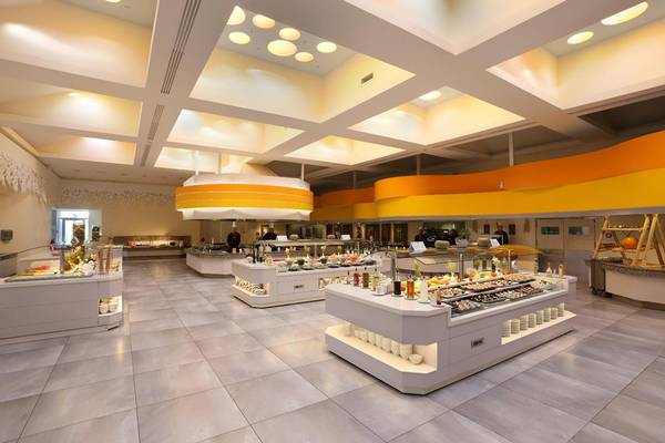Innenansicht des Restaurants im Lyttos Beach Hotel mit Speisenbuffets und gelben Wänden.