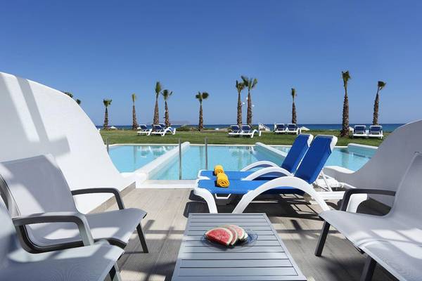 Terrasse mit Pool und Liegen im Lyttos Beach Hotel mit Blick auf das Meer und Palmen