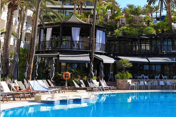 Poolbereich des Corallium Dunamar Garden by Lopesan Hotels mit Loungeliegen und einem kleinen Gebäude